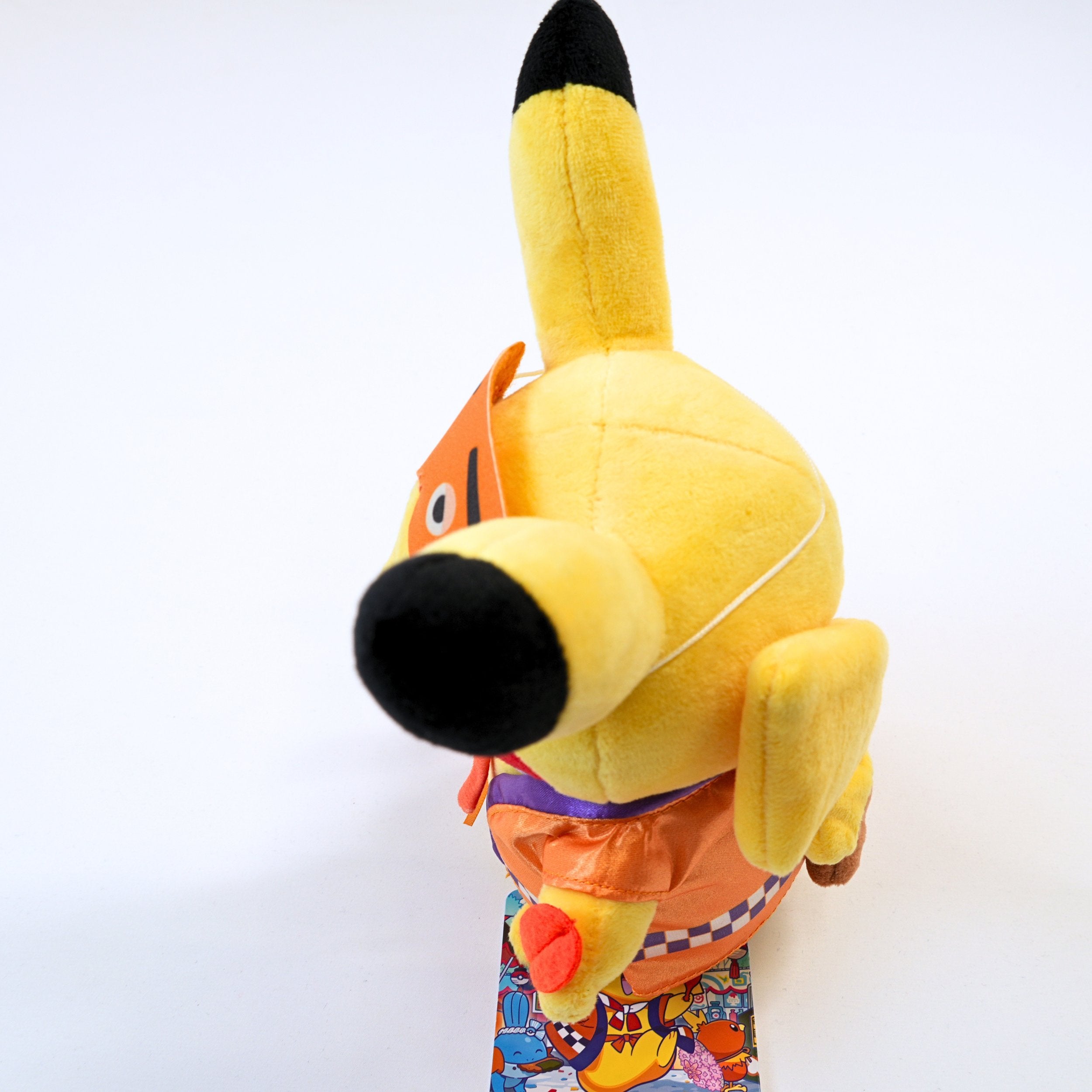 Vista lateral del peluche Pokémon Center Fukuoka R Pikachu Niwaka Mask, mostrando el volumen del peluche, la ropa y los detalles laterales