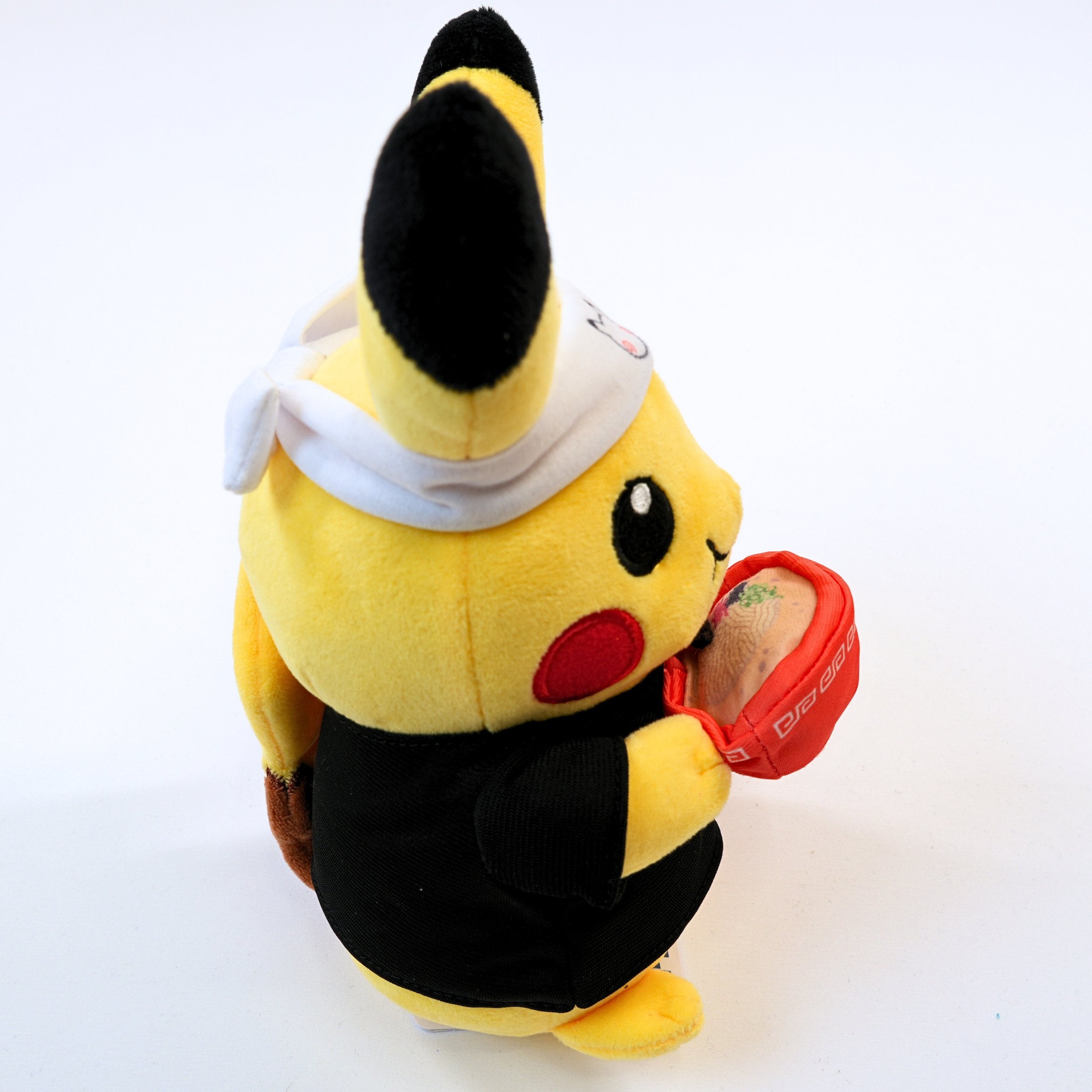 Vista del otro lateral del peluche Pokémon Center Fukuoka R Ramen Pikachu, mostrando los detalles laterales del traje y el acabado del peluche