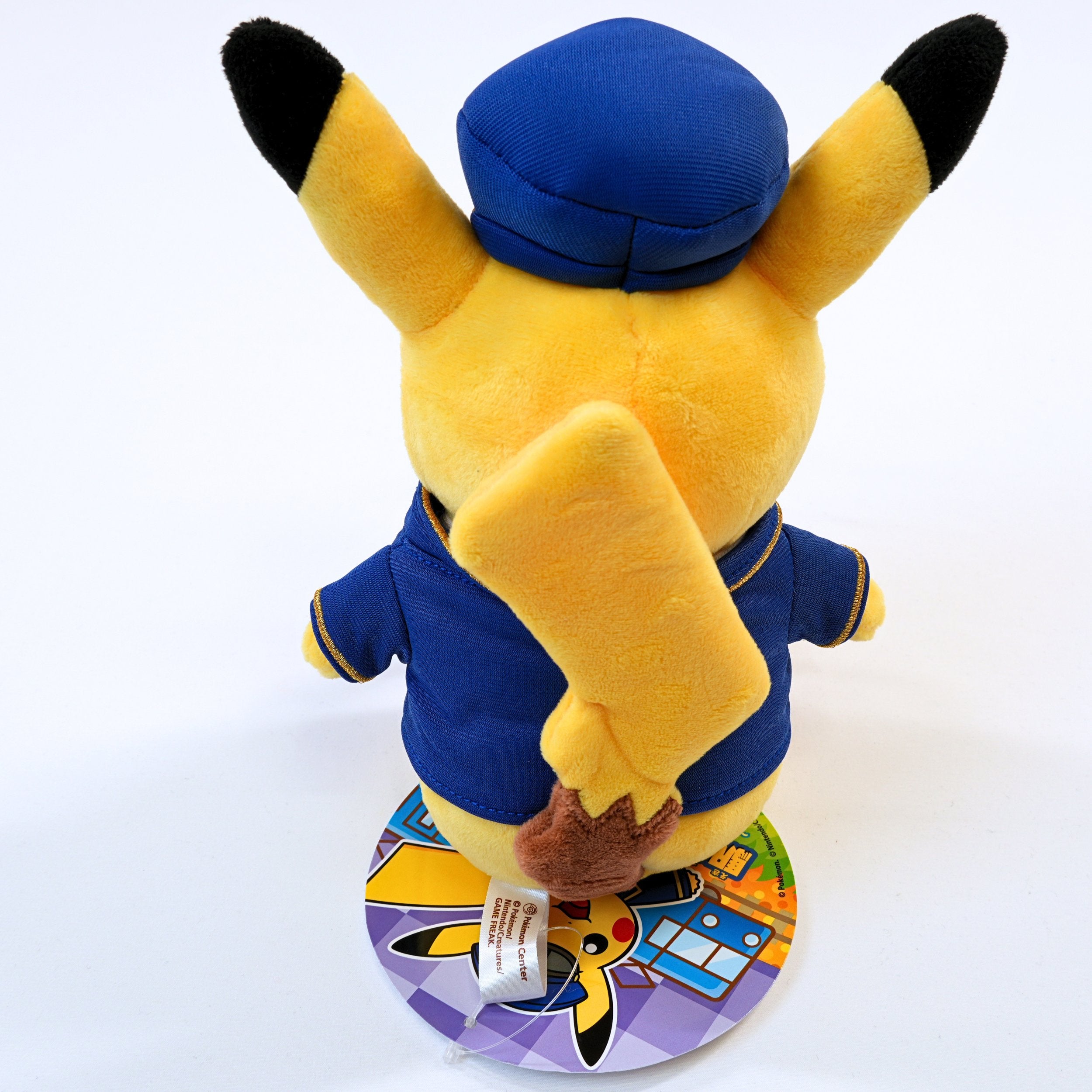 Vista trasera del peluche Pokémon Store Tokyo Station Station Master Pikachu, mostrando la espalda, la cola y la etiqueta del producto